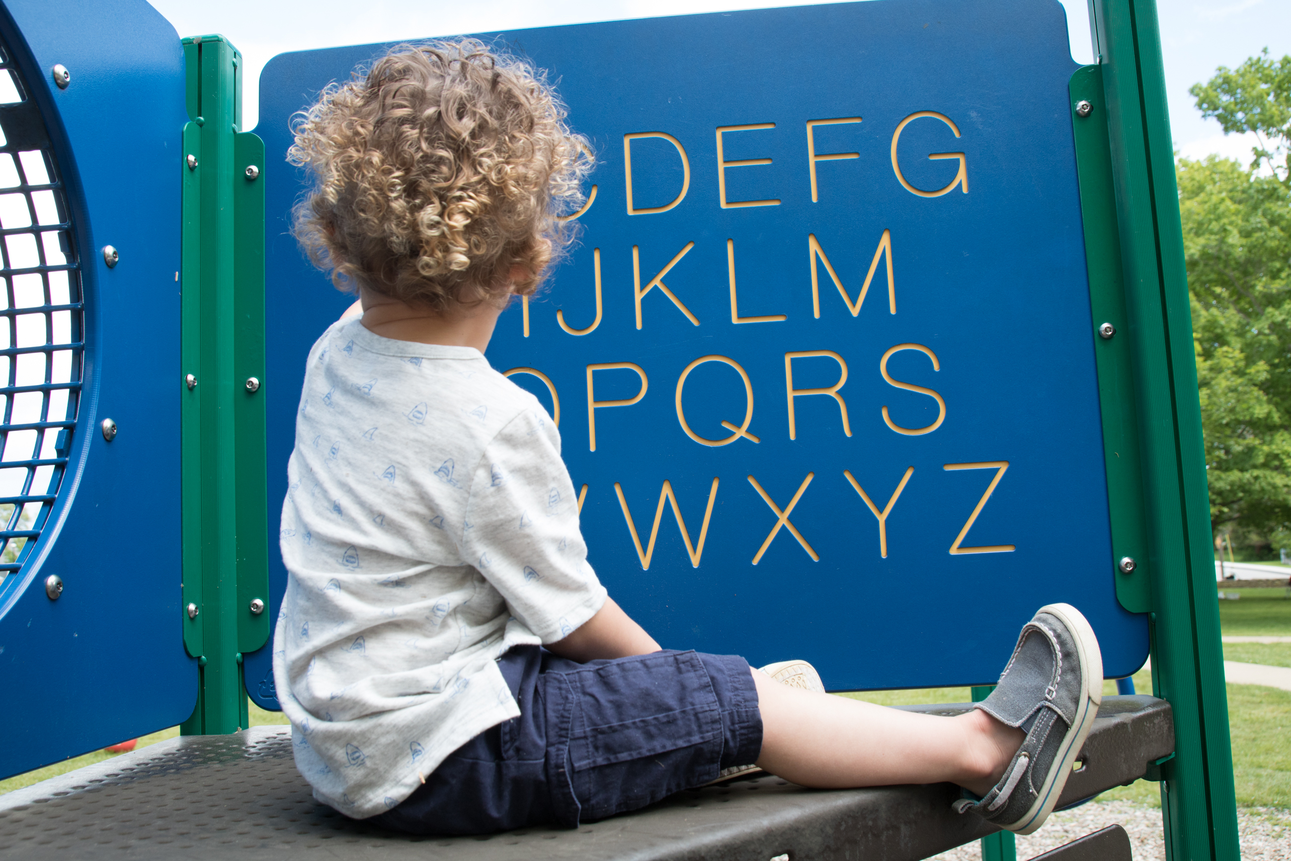 preschooler looking at alphabet display on playground